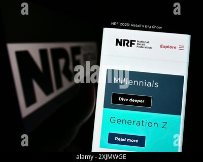 Stuttgart, Deutschland, 12.02.2022: Person, die ein Mobiltelefon hält, mit Webseite des US-Verbands National Retail Federation (NRF) auf dem Bildschirm mit Logo. Fokus Stockfoto