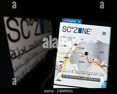 Stuttgart, Deutschland, 12.04.2022: Person, die ein Mobiltelefon hält, mit Website der ägyptischen Suez Canal Economic Zone (SCZONE) vor dem Logo auf dem Bildschirm. Fokus Stockfoto