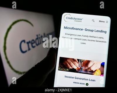 Stuttgart, Deutschland, 12.10.2022: Person, die ein Mobiltelefon hält, mit Webseite des indischen Unternehmens CreditAccess Grameen Limited auf dem Bildschirm vor dem Logo. Stockfoto