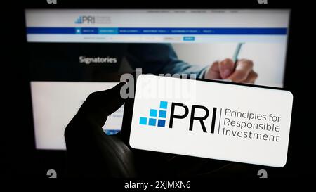 Stuttgart, 19.12.2022: Person, die ein Mobiltelefon mit dem Logo der UN Principles for Responsible Investment (PRI) auf dem Bildschirm vor der Webseite hält. Stockfoto