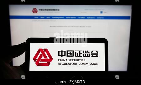 Stuttgart, 29.12.2022: Person, die ein Mobiltelefon hält, mit dem Logo der chinesischen Wertpapieraufsichtsbehörde (CSRC) auf dem Bildschirm vor der Webseite. Stockfoto