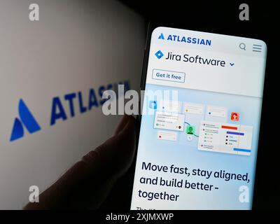 Stuttgart, Deutschland, 12-30-2022: Person, die ein Smartphone hält, mit der Webseite des australischen Softwareunternehmens Atlassian Corporation auf dem Bildschirm mit Logo. Stockfoto