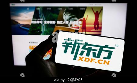 Stuttgart, 23.12.2022: Person, die ein Smartphone mit dem Logo der New Oriental Education and Technology Group auf dem Bildschirm vor der Website hält. Stockfoto