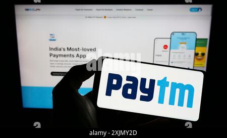 Stuttgart, 23.12.2022: Person, die ein Mobiltelefon mit dem Logo des indischen digitalen Zahlungsunternehmens Paytm auf dem Bildschirm vor dem Business Web hält Stockfoto