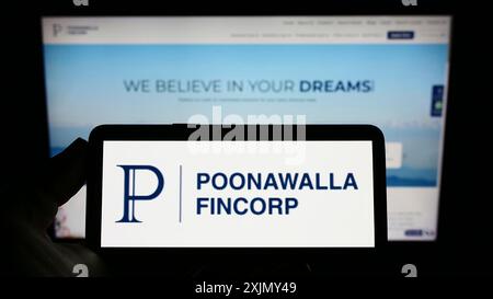 Stuttgart, Deutschland, 12-30-2022: Person, die ein Smartphone mit dem Logo des Finanzunternehmens Poonawalla Fincorp Limited auf dem Bildschirm vor der Website hält. Stockfoto