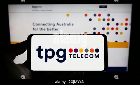 Stuttgart, Deutschland, 12-30-2022: Person, die ein Mobiltelefon mit dem Logo des australischen Unternehmens TPG Telecom Limited auf dem Bildschirm vor der Unternehmenswebseite hält. Stockfoto