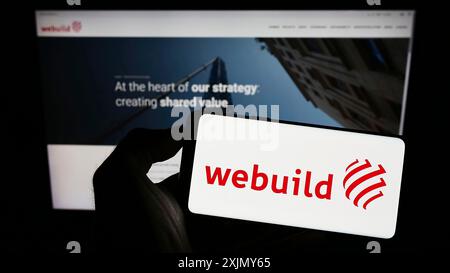 Stuttgart, Deutschland, 12.30.2022: Person mit Mobiltelefon mit Logo des italienischen Bauunternehmens Webuild Spa auf dem Bildschirm vor dem Geschäft Stockfoto