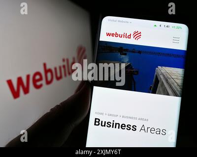Stuttgart, Deutschland, 12.30.2022: Person, die ein Handy hält, mit Webseite des italienischen Bauunternehmens Webuild S.p.A. auf dem Bildschirm vor dem Logo. Stockfoto