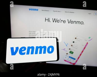 Stuttgart, Deutschland, 12-31-2022: Person, die ein Mobiltelefon mit dem Logo des mobilen Zahlungsdienstes Venmo auf dem Bildschirm vor der Business-Webseite hält. Fokus Stockfoto