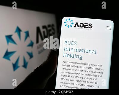 Stuttgart, 25.12.2022: Person, die ein Mobiltelefon hält, mit Website des ägyptischen Unternehmens ADES International Holding auf dem Bildschirm vor dem Logo. Stockfoto