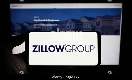 Stuttgart, Deutschland, 01.01.2023: Person, die ein Mobiltelefon mit dem Logo der US-Immobiliengesellschaft Zillow Group Inc. Auf dem Bildschirm vor dem Geschäft hält Stockfoto