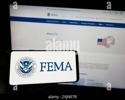 Stuttgart, Deutschland, 01-08-2023: Person, die ein Smartphone mit dem Siegel der Bundesagentur für Notfallmanagement (FEMA) auf dem Bildschirm vor der Website hält. Stockfoto