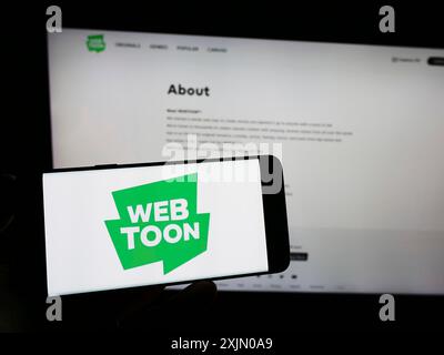 Stuttgart, Deutschland, 13.01.2023: Person mit Smartphone mit Logo der Digital Comic-Firma WEBTOON Entertainment Inc. Auf dem Bildschirm vor Stockfoto