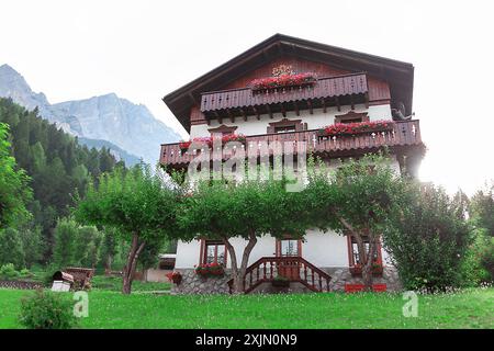 Das Haus ist von Bäumen umgeben und hat einen wunderschönen Blick auf die Berge. Gebäude mit Balkon und Garten davor Stockfoto