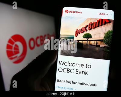 Stuttgart, Deutschland, 01.12.2023: Person, die ein Handy hält, mit Website der Oversea-Chinese Banking Corporation (OCBC Bank) auf dem Bildschirm mit Logo. Fokus Stockfoto