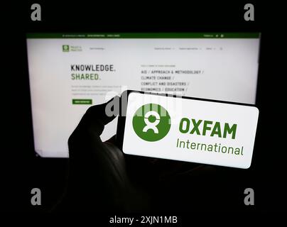 Stuttgart, Deutschland, 21.01.2023: Person, die ein Mobiltelefon mit dem Logo der konföderation Oxfam International auf dem Bildschirm vor der Webseite hält. Konzentrieren Sie sich auf das Telefon Stockfoto