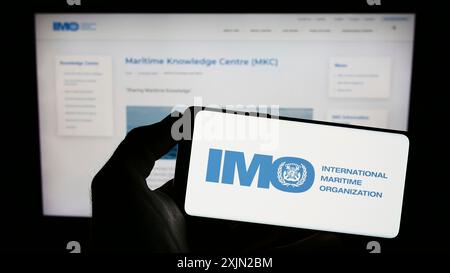 Stuttgart, Deutschland, 03.07.2023: Person mit Mobiltelefon mit Logo der Internationalen Seeschifffahrtsorganisation (IMO) auf dem Bildschirm vor der Webseite. Fokus Stockfoto