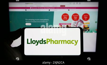 Stuttgart, Deutschland, 03.07.2023: Person, die ein Mobiltelefon mit dem Logo des britischen Unternehmens LloydsPharmacy Limited auf dem Bildschirm vor dem Business Web hält Stockfoto