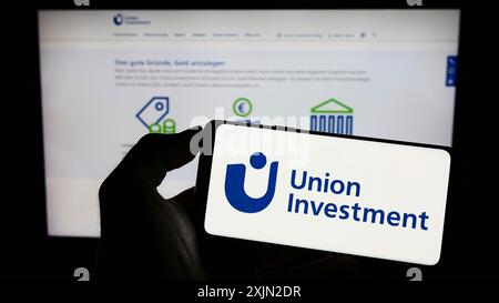 Stuttgart, Deutschland, 29.01.2023: Person mit Mobiltelefon mit Logo der deutschen Investmentgesellschaft Union Investment auf dem Bildschirm vor dem Unternehmen Stockfoto