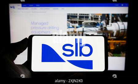 Stuttgart, Deutschland, 03.09.2023: Person mit Mobiltelefon mit Logo der Ölfeldfirma Schlumberger Limited (SLB) auf dem Bildschirm vor dem Geschäft Stockfoto