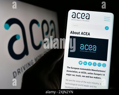 Stuttgart, Deutschland, 03-12-2023: Person mit Handy und Website des European Automobile Manufacturers Association (ACEA) auf dem Bildschirm. Konzentrieren Sie sich auf Stockfoto