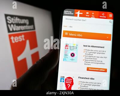 Stuttgart, Deutschland, 03-10-2023: Person mit Smartphone mit Webseite der Stiftung Warentest auf dem Bildschirm mit Logo. Fokus Stockfoto