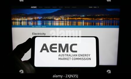 Stuttgart, Deutschland, 13.03.2023: Person, die ein Smartphone mit dem Logo der Australian Energy Market Commission (AEMC) auf dem Bildschirm vor der Website hält. Stockfoto