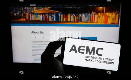 Stuttgart, Deutschland, 13.03.2023: Person mit Mobiltelefon mit Logo der Australian Energy Market Commission (AEMC) auf dem Bildschirm vor der Webseite. Stockfoto