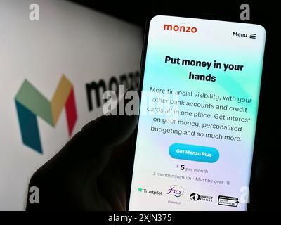 Stuttgart, Deutschland, 13.03.2023: Person, die ein Smartphone hält, mit Webseite des britischen Bankunternehmens Monzo Bank Limited auf dem Bildschirm mit Logo. Konzentrieren Sie sich auf Stockfoto
