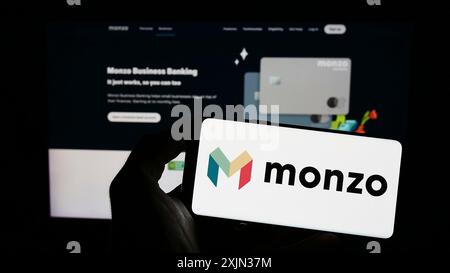 Stuttgart, Deutschland, 13.03.2023: Person, die ein Mobiltelefon mit dem Logo der britischen Bankgesellschaft Monzo Bank Limited vor dem Geschäft auf dem Bildschirm hält Stockfoto