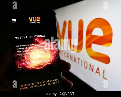 Stuttgart, Deutschland, 19.03.2023: Person, die ein Smartphone hält, mit Website des Unterhaltungsunternehmens Vue International auf dem Bildschirm vor dem Logo. Fokus Stockfoto
