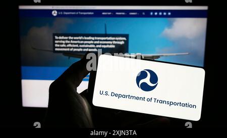Stuttgart, Deutschland, 22.03.2023: Person, die ein Smartphone hält, mit dem Logo des US-Verkehrsministeriums (USDOT) vor dem Bildschirm Stockfoto