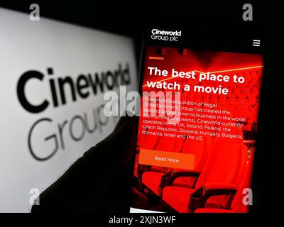 Stuttgart, Deutschland, 19.03.2023: Person, die ein Smartphone hält, mit Webseite des britischen Kinounternehmens Cineworld Group plc auf dem Bildschirm vor dem Logo. Stockfoto