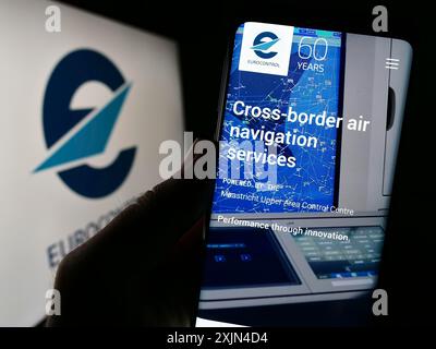 Stuttgart, Deutschland, 04.01.2023: Person, die ein Mobiltelefon hält, mit Webseite der Flugverkehrsmanagementorganisation Eurocontrol auf dem Bildschirm mit Logo. Fokus Stockfoto