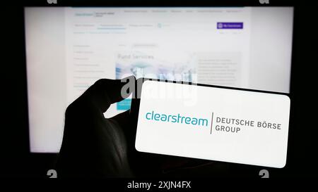 Stuttgart, Deutschland, 04.01.2023: Person, die ein Mobiltelefon mit dem Logo der Firma Clearstream International SA auf dem Bildschirm vor der Website des Unternehmens hält. Stockfoto