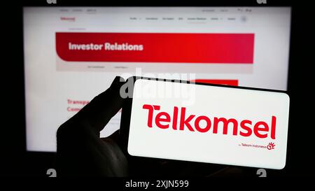 Stuttgart, 24.04.2023: Person, die ein Smartphone mit dem Logo der Firma PT Telekunikasi Selular (Telkomsel) auf dem Bildschirm vor der Website hält. Stockfoto