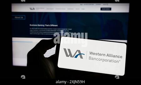 Stuttgart, 24.04.2023: Person, die ein Mobiltelefon mit dem Logo der amerikanischen Firma Western Alliance Bancorporation auf dem Bildschirm vor der Webseite hält. Stockfoto