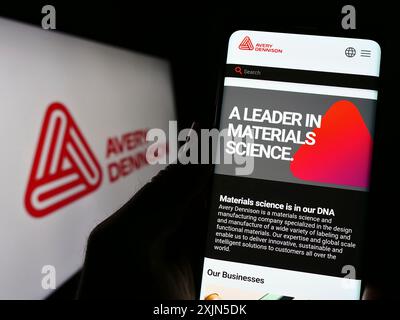 Stuttgart, Deutschland, 28.04.2023: Person, die ein Smartphone hält, mit der Webseite des US-amerikanischen Verpackungsunternehmens Avery Dennison Corporation auf dem Bildschirm mit Logo. Fokus Stockfoto