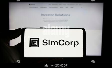 Stuttgart, Deutschland, 28.04.2023: Person, die ein Mobiltelefon mit dem Logo des dänischen Finanzsoftwareunternehmens SimCorp auf dem Bildschirm vor der Webseite hält. Stockfoto