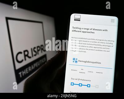 Stuttgart, Deutschland, 21.04.2023: Person, die ein Mobiltelefon hält, mit Webseite des Biotechnologie-Unternehmens CRISPR Therapeutics AG auf dem Bildschirm mit Logo. Konzentrieren Sie sich auf Stockfoto