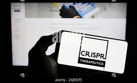 Stuttgart, 21.04.2023: Person mit Mobiltelefon mit Logo des Biotechnologie-Unternehmens CRISPR Therapeutics AG auf dem Bildschirm vor der Webseite. Stockfoto