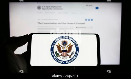 Stuttgart, Deutschland, 04.04.2023: Person mit Handy mit Logo der Kommission für Chancengleichheit (EEOC) auf dem Bildschirm vor der Webseite. Stockfoto