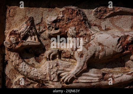 Löwe mit mächtigen Klauen besiegt den brüllenden Drachen. Skulptur aus rotem Porphyr von Veronese, Chiesa di Sant’Apollinare in Trient, Trentino-Südtirol, Italien. Stockfoto