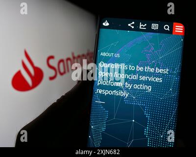 Stuttgart, Deutschland, 16.04.2023: Person, die ein Mobiltelefon hält, mit Webseite der spanischen Bankgesellschaft Banco Santander SA auf dem Bildschirm vor dem Logo. Fokus Stockfoto