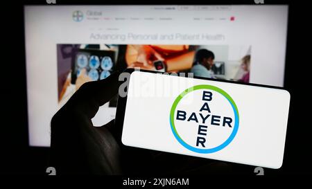 Stuttgart, Deutschland, 16.04.2023: Person, die ein Mobiltelefon mit dem Logo des deutschen Pharmaunternehmens Bayer AG auf dem Bildschirm vor der Business-Website hält. Stockfoto