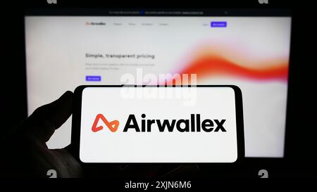 Stuttgart, Deutschland, 26.03.2023: Person, die ein Smartphone mit dem Logo des Finanztechnikunternehmens Airwallex auf dem Bildschirm vor der Website hält. Konzentrieren Sie sich auf Stockfoto