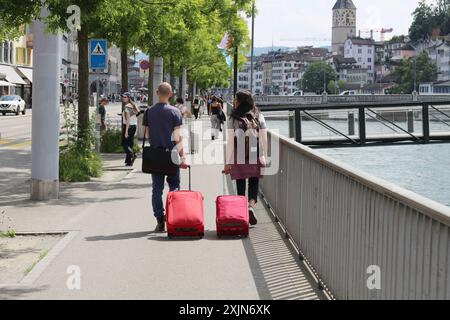 Zwei Touristen, die rote Handgepäckstücke ziehen, kamen neu in der belebten Stadt Zürich an. Perfekt für Reisethemen, Tourismuswerbung und c Stockfoto