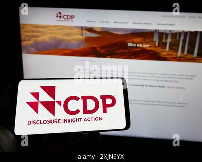 Stuttgart, 25.03.2023: Person, die ein Mobiltelefon hält, mit dem Logo der Organisation Carbon Disclosure Project (CDP) auf dem Bildschirm vor der Webseite. Stockfoto