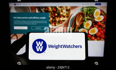 Stuttgart, Deutschland, 19.03.2023: Person, die ein Smartphone mit dem Logo von WW International Inc. (Weight Watchers) auf dem Bildschirm vor der Website hält. Fokus Stockfoto