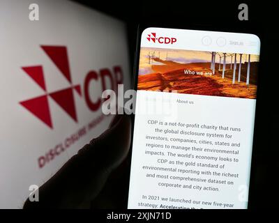 Stuttgart, 25.03.2023: Person, die ein Handy hält, mit Webseite der Organisation Carbon Disclosure Project (CDP) auf dem Bildschirm mit Logo. Konzentrieren Sie sich auf Stockfoto